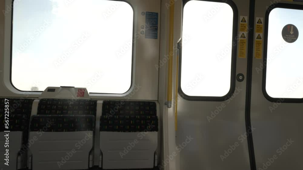 Poster inside view of empty folded up seats on metropolitan line train carriage with bright sunshine and su