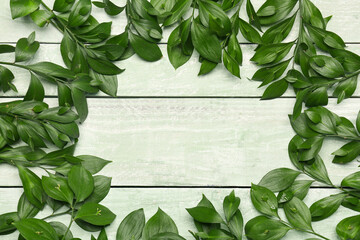 Frame made of fresh plant branches on color wooden background
