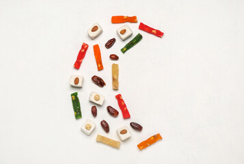 Crescent made of dried sweets for Ramadan on white background
