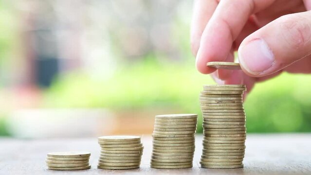 Men's hands stacking growing piles of silver coins Money concept and saving money on green nature background