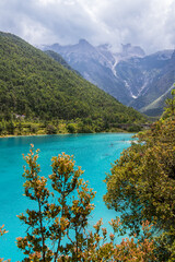 Autumn trees in front of the stunning turquoise lake at the Blue Moon Valley in Lijiang, Sichuan,...