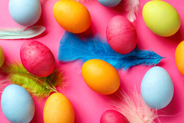 Fototapeta na wymiar Composition with colorful Easter eggs and feathers on pink background