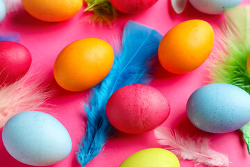 Fototapeta na wymiar Composition with colorful Easter eggs and feathers on pink background, closeup