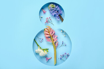 Spring flowers visible through cut color paper in shape of figure 8. Women's Day celebration