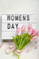 Bouquet of beautiful tulip flowers and board with text Women's Day on light background, closeup