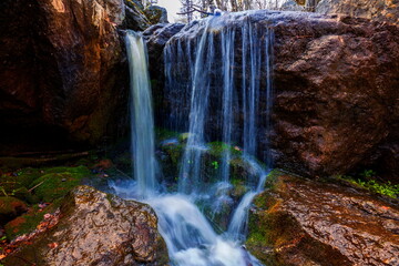 picturesque waterfall on a stream running from the mountains along a ravine on a spring day