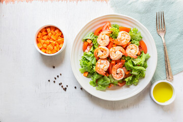 Healthy food shrimp salad lettuce carrot tomato in bowl on wood background.