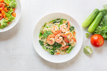 Fried rice with shrimp has vegetable in plate on white table.