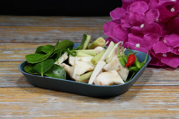 Pile of ingredient set of famous Thai spicy soup (Tom-yum soup) in Asia restaurant. Mock up of fresh and organic spices on the plate.