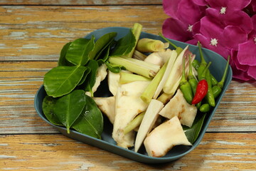 Pile of ingredient set of famous Thai spicy soup (Tom-yum soup) in Asia restaurant. Mock up of fresh and organic spices on the plate.