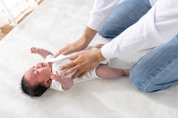 泣く赤ちゃんをあやす男性の手（0歳2ヶ月・日本人・男の子）