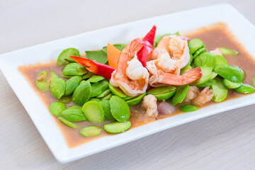 Phad Sato, stir-fried prawns with curry paste (Thai food), white plate, placed on a wooden table