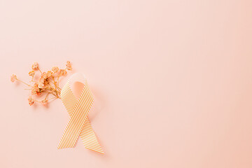 Pink awareness ribbon sign and paper card flower of World Cancer Day on pink background with copy space, concept of medical and health care support, Breast cancer awareness concept, 4 February