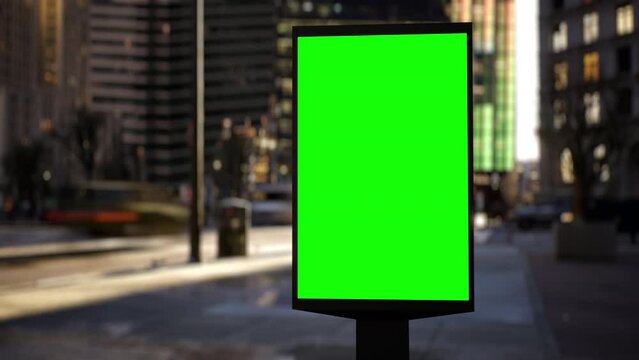 Modern billboard with a green screen for advertising on a busy crossroad street with traffic and skyscrapers, timelapse of traffic at sunset. Loop video.