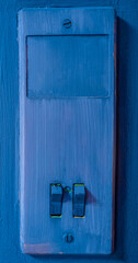 Blue old light switch on the wall close-up.