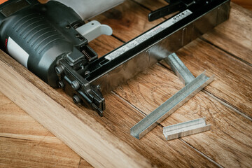 Upholstery Stapler with  Staples on wooden desk in workshop.  Carpentry Woodworking and DIY...