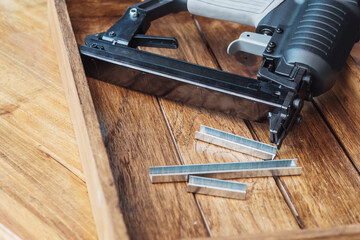 Gauge Staple Gun, Upholstery Stapler with  Staples on wooden desk in workshop.  Carpentry...