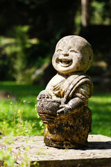 Child monk happy smiling laughing face doll Buddha, old stone art statue decoration in outdoor...