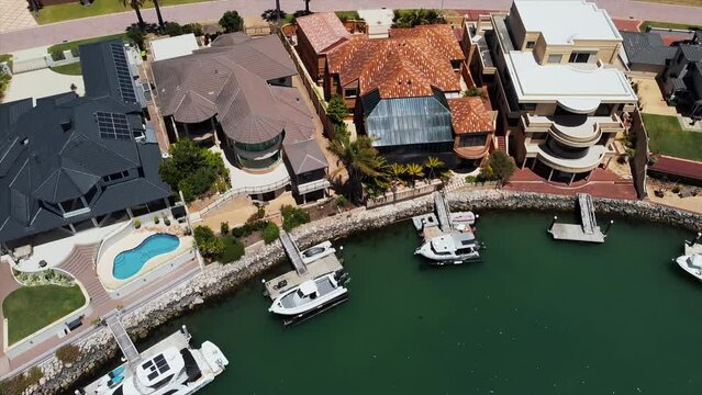 Aerial view of luxury townhouses by the sea, with private dock for boats. Drone view of marina bay residence with moored boats on private pier.