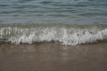 Soft blue ocean wave on clean sandy beach. Selective focus