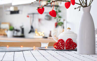 Valentine decor on table of white kitchen in cozy home. Copy space. Gift for valentines day, family love nest. A vase with a bouquet of hearts in a modern interior.
