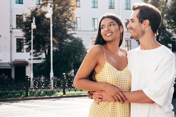 Smiling beautiful woman and her handsome boyfriend. Happy cheerful family. Sexy couple posing in the street at sunrise. During romantic date at sunny summer day outdoors. Looking at each other