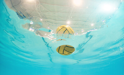 Water polo, sport and ball in a pool from below with equipment floating on the surface during a...