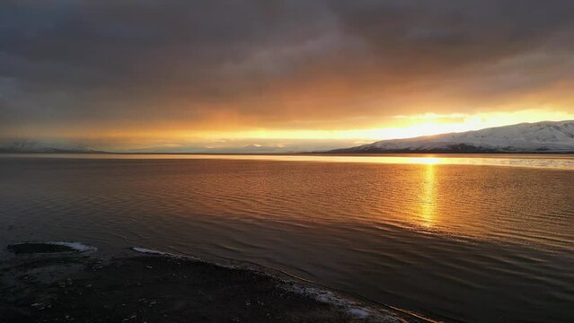 Flying along the shoreline of Utah Lake reflecting the sunset during winter.