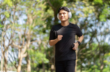 Man running wearing white headphone and smart watch while running or jogging at park. Sport healthy...