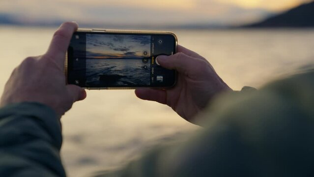 Man Using Phone To Capture Photos Of The Waves During Sunrise