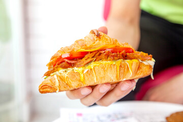 Brioche croissant grilled chicken sandwich in hand lifestyle food photography.