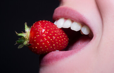 Strawberry in lips. Healthy teeth. Red strawberry in woman mouths close up.