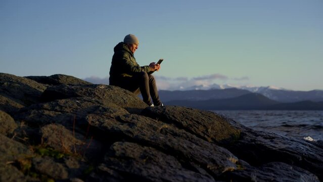 Man Sitting And Taking A Photo Of The View At Sunrise