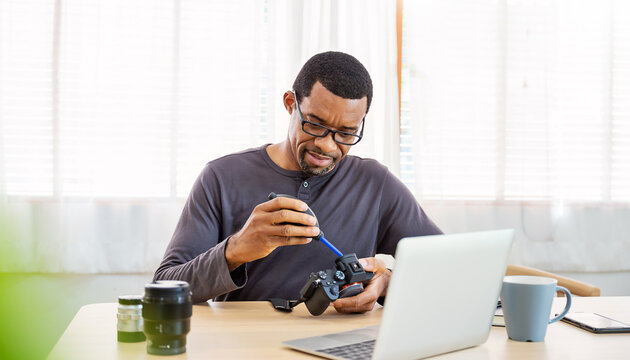 Portrait of African black photographer creative man working in office holding camera laptop. Business people employee freelance online marketing. Successful freelance creative artist guy business.