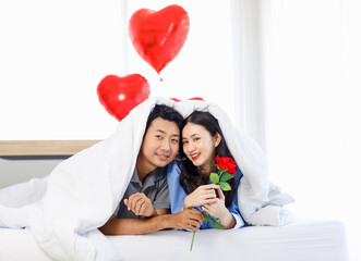 Asian young romantic lover couple male boyfriend giving red rose surprising female girlfriend...