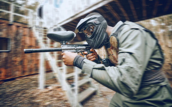 Paintball, black man and games, gun and target, sport with fitness and battlefield challenge, war soldier outdoor. Motion blur, extreme sports and exercise, shooting range and military mission