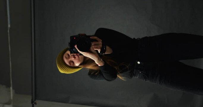 a girl in black clothes and a mustard-colored hat pictures herself in the reflected mirrors. the girl is filming herself. hipster vertical video
