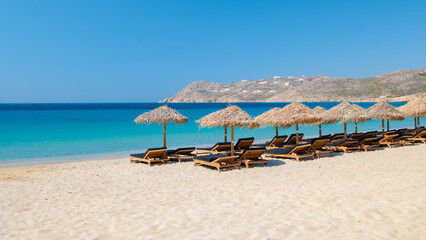 Mykonos beach during summer with umbrella and luxury beach chairs beds, blue ocean at Elia beach - obrazy, fototapety, plakaty