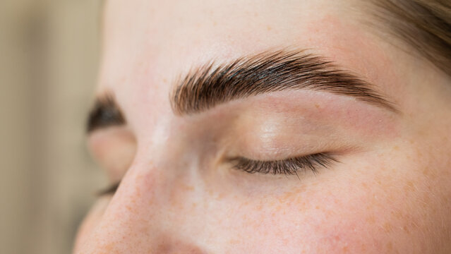 Close-up portrait of a woman after the procedure of correction and lamination of eyebrows. 