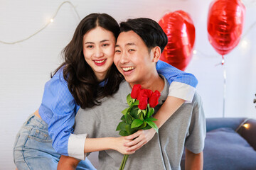 Asian young romantic lover couple female girlfriend holding red roses bouquet hugging cuddling...