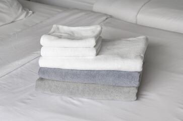 folded terry towels lie on clean white bed. Cleaning in guest room of hotel, cleanliness, laundry