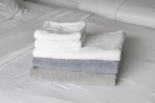 Folded Terry Towels Lie On Clean White Bed. Cleaning In Guest Room Of Hotel, Cleanliness, Laundry