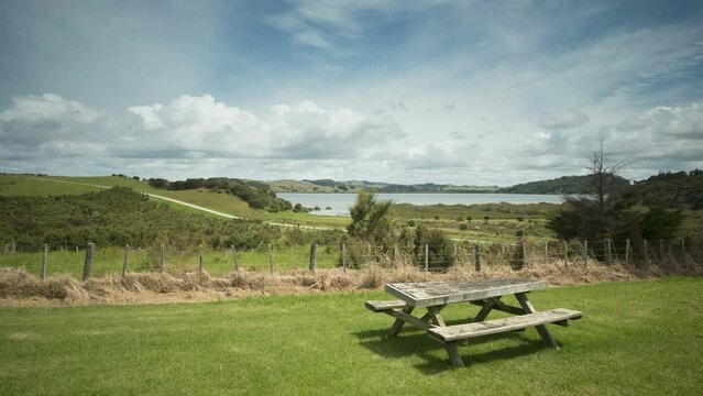 Time lapse, on a sunny day, overlooking the Ohuawharo River and Solomon's Bay from Aitu Regional Park, Auckland, New Zealand. Rustic, wooden picnic table in the foreground.