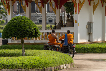 Phuket. Thailand. November 15 2022.Two thai buddhist monks driving a motorbike inside buddhist temple