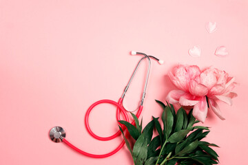 Pink peony and stethoscope on pink background with copy space.