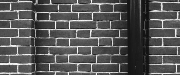 Minimalist fragment of brick wall with downspout close up. Beautiful brick backdrop with drain pipe. Geometric and symmetrical background of brick wall pattern. Modern design of interior or exterior.