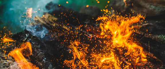 Vivid smoldered firewoods burned in fire close-up. Atmospheric background with orange flame of...