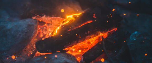 Vivid smoldered firewoods burned in fire closeup. Atmospheric background with orange flame of...