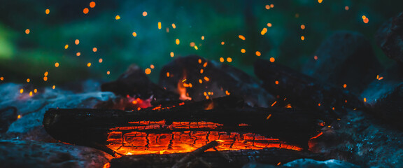 Vivid smoldered firewoods burned in fire closeup. Atmospheric background with orange flame of...