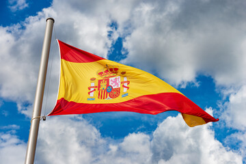 Closeup of a Spanish flag blowing in the wind against a blue sky with clouds and copy space. Spain...